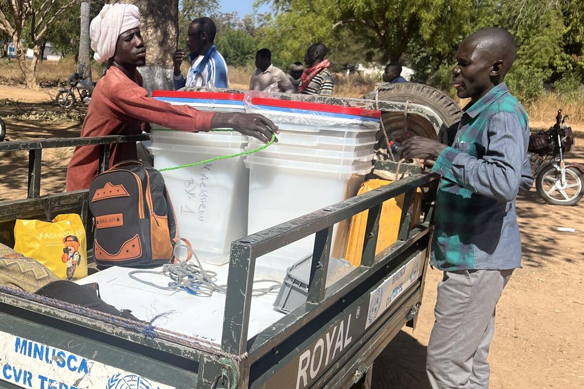 Des personnes attachent des conteneurs de stockage à un véhicule de la MINUSCA.