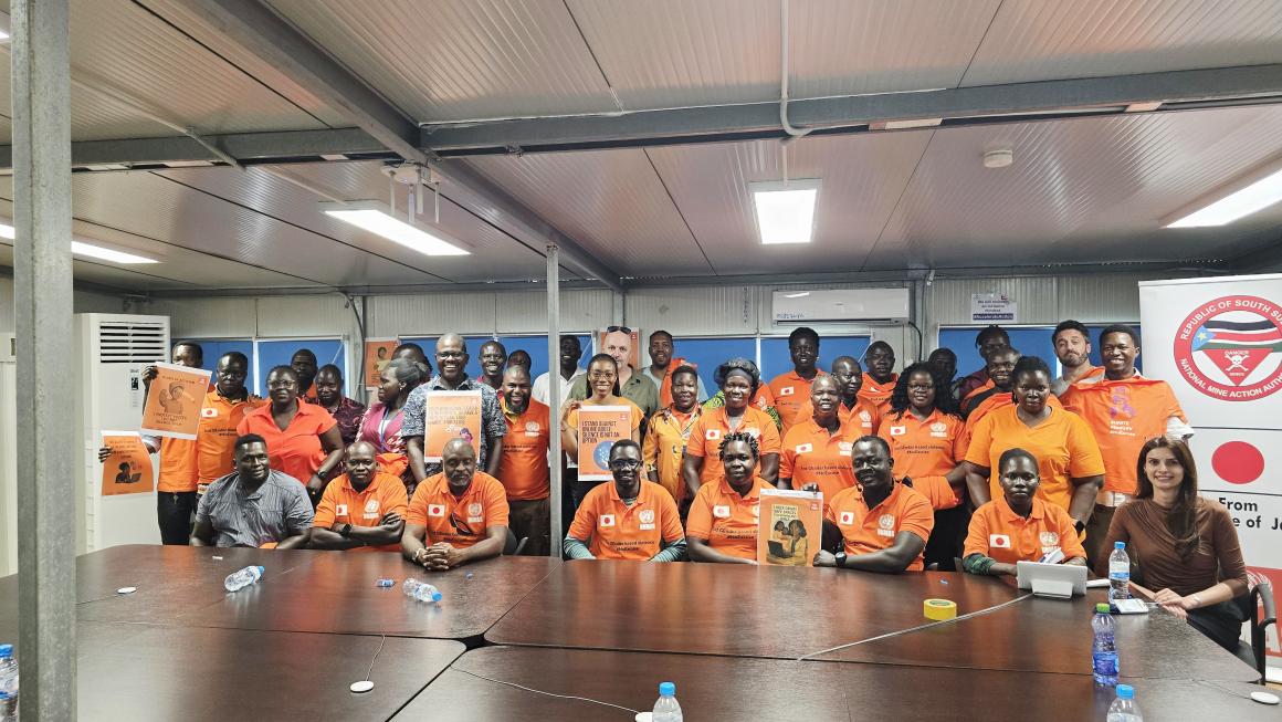 a group of people in orange shirt with a banner behind them.